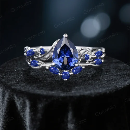 A complete bridal set featuring a vintage pear cut blue sapphire engagement ring paired with a matching nature-inspired twig vine band, showcasing the cohesive antique design.