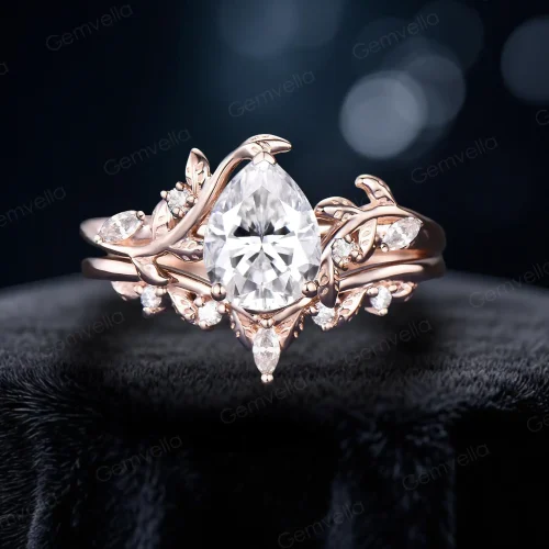 Front view of a 1.25 carat pear-shaped moissanite bypass engagement ring set in 14K rose gold, featuring intricate leaf and vine branch detailing wrapping around the center stone, showcasing the nature-inspired design and brilliant moissanite sparkle.