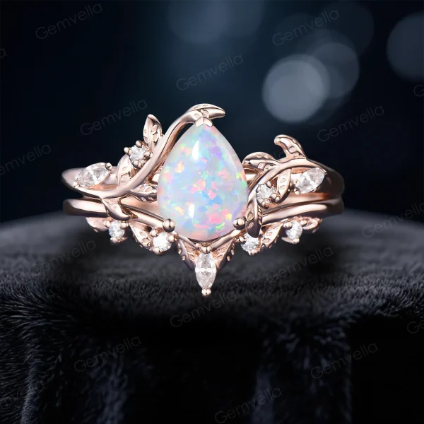 Front view of a 1.25 carat pear cut white opal ring set in 14k rose gold, featuring a nature inspired leaf vine bypass design with an engagement ring and matching wedding band.
