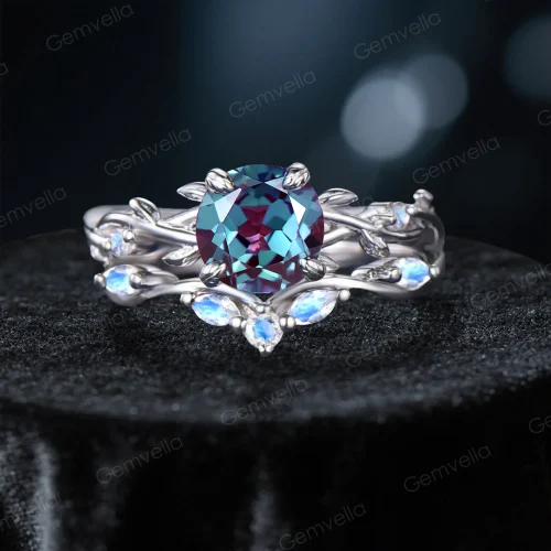 Frontal view of a nature-inspired bridal ring set featuring a color-changing round cut Alexandrite center stone, surrounded by an intricate sterling silver twisting vine and leaf setting with glowing blue Moonstone gems.