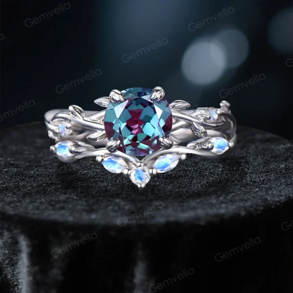 Frontal view of a nature-inspired bridal ring set featuring a color-changing round cut Alexandrite center stone, surrounded by an intricate sterling silver twisting vine and leaf setting with glowing blue Moonstone gems.