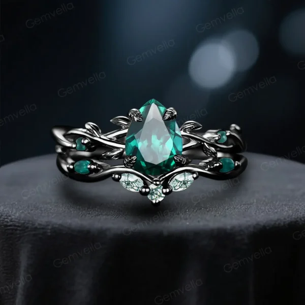 Front view of a black gold ring set featuring a 1.25ct pear cut emerald and moss agate, showcasing the intricate twig vine gothic design for engagement and wedding.