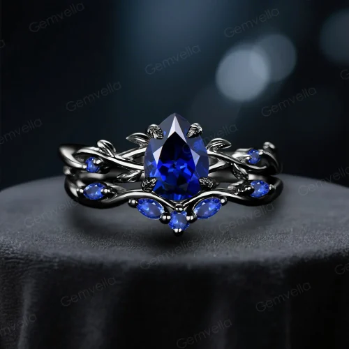Front view of a black gold ring set featuring a 1.25ct pear cut blue sapphire, showcasing the intricate twig vine gothic design for engagement and wedding.
