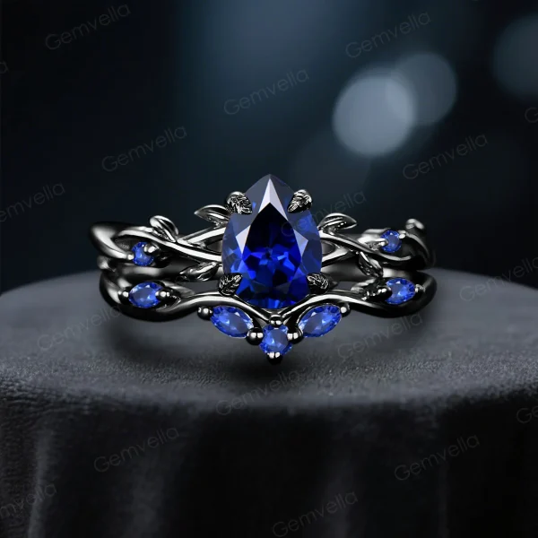 Front view of a black gold ring set featuring a 1.25ct pear cut blue sapphire, showcasing the intricate twig vine gothic design for engagement and wedding.