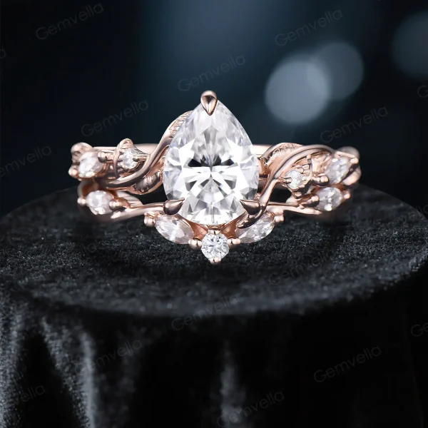 Front view of a nature inspired moissanite engagement ring set featuring a 1.25ct pear cut center stone, surrounded by delicate leaf vine and branch detailing on the twist band