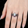 Real wear shot of nature-inspired engagement ring set with 1.25ct pear-cut opal in black gold, twig vine design on hand