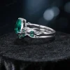 A side view showcasing the height and craftsmanship of the vintage pear cut emerald engagement ring set with nature-inspired twig vine designs.