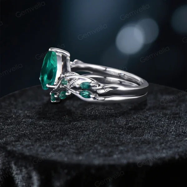 A side view showcasing the height and craftsmanship of the vintage pear cut emerald engagement ring set with nature-inspired twig vine designs.