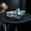 An angled photograph of the vintage pear cut emerald engagement ring set, revealing the unique interplay of light on its twig vine details and showcasing its dynamic, nature-inspired design from a three-quarter perspective.