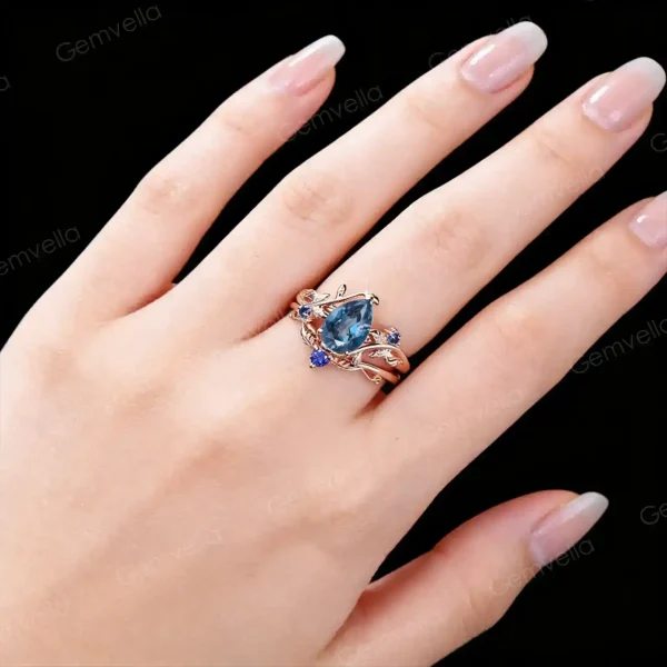 Close-up of a hand wearing the 1.25ct London blue topaz engagement ring and blue sapphire wedding band, showcasing how the nature-inspired leaf-branch design looks on the finger.