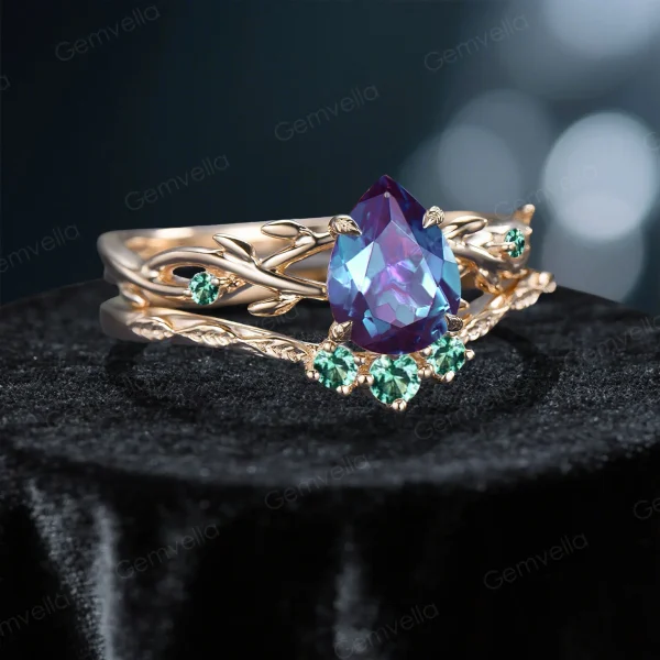 Side profile shot of the 1.25ct pear shaped alexandrite ring on a yellow gold band, highlighting the prong setting height, the curvature of the matching wedding band, and the organic vine texture.