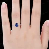 Lifestyle image of a woman wearing the 1.5ct oval blue sapphire and moissanite engagement ring, showing the fit and sparkle on the finger.