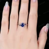 A close-up lifestyle photo of a woman's hand wearing the blue sapphire and rose gold leaf vine ring, demonstrating how it looks as an engagement ring.