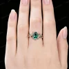 Close up of 1.5ct oval emerald bridal ring set worn on hand, featuring 10K rose gold leaf vine branch design for vintage wedding or anniversary look