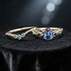 Flat lay photography of the nature inspired alexandrite engagement ring and wedding band set separated to show the intricate emerald leaf details and the pear shaped center stone.