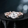 Front view of a vintage rose gold moissanite engagement ring featuring a round cut center stone surrounded by delicate leaf vine nature inspired setting, showcasing the diamond alternative gemstone and intricate bridal ring design