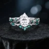 A set of vintage-inspired moissanite engagement rings featuring a twig vine design, with a pear-cut moissanite stone and emerald accents.