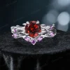 Frontal view of a nature-inspired bridal ring set featuring a vibrant round cut Natural Red Garnet center stone, surrounded by an intricate sterling silver twisting vine and leaf setting adorned with sparkling purple Amethyst gems.
