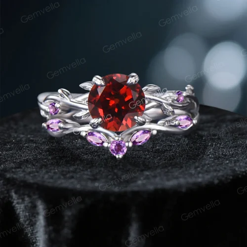 Frontal view of a nature-inspired bridal ring set featuring a vibrant round cut Natural Red Garnet center stone, surrounded by an intricate sterling silver twisting vine and leaf setting adorned with sparkling purple Amethyst gems.