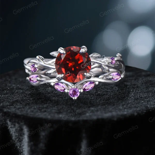 Frontal view of a nature-inspired bridal ring set featuring a vibrant round cut Natural Red Garnet center stone, surrounded by an intricate sterling silver twisting vine and leaf setting adorned with sparkling purple Amethyst gems.