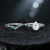 Flat lay image of the vintage nature inspired moissanite engagement ring set, displaying the pear cut and emerald cut rings side-by-side with detailed twig vine band craftsmanship.