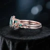 Side profile showcasing the 10k rose gold band, leaf vine branch design, and the profile of the 1.5ct oval moss agate and emerald stones.