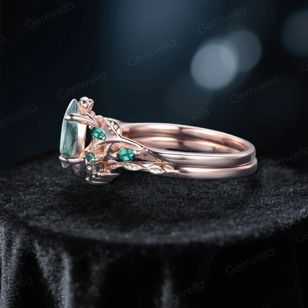 Side profile showcasing the 10k rose gold band, leaf vine branch design, and the profile of the 1.5ct oval moss agate and emerald stones.