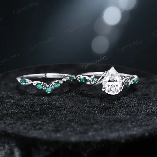Flat lay image of the vintage nature inspired moissanite engagement ring set, displaying the pear cut and emerald cut rings side-by-side with detailed twig vine band craftsmanship.