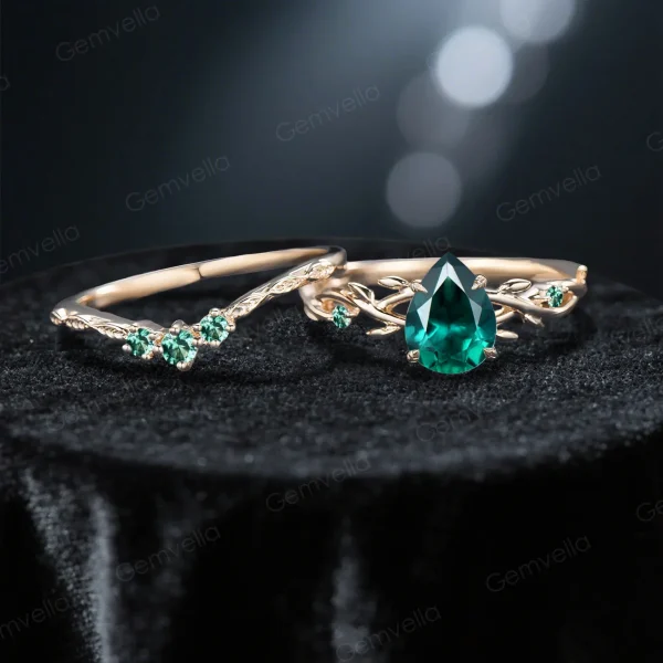 Flat lay photography of the nature inspired emerald engagement ring and wedding band set separated to show the intricate leaf details and the deep green gemstone.