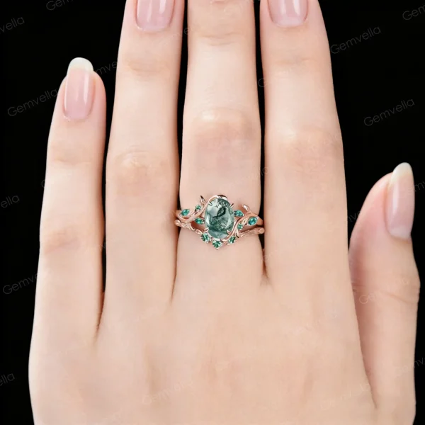 Close-up image of a woman's hand wearing the 1.5ct moss agate and emerald bridal set, showcasing how the 10k rose gold nature inspired leaf vine ring looks on a finger.