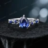 Direct front view of the pear cut blue sapphire center stone in the vintage twig engagement ring, highlighting the symmetrical vine details flanking the stone.