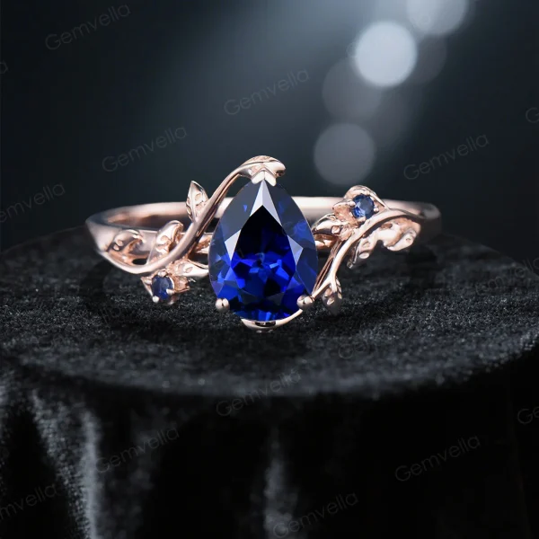 Detailed close up of the 1.25ct pear cut blue sapphire center stone held by delicate handmade leaf prongs in the engagement ring