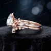 Side profile view of a 1.25ct pear cut moissanite engagement ring showing the bypass setting design, 14K rose gold band with delicate leaf and vine branch accents, and the height of the nature-inspired bridal ring setting.