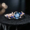 Angled side view of the 1ct London Blue Topaz and Blue Sapphire ring, providing a 3D perspective of the vintage rose gold setting, gemstone depth, and intricate nature-inspired details.