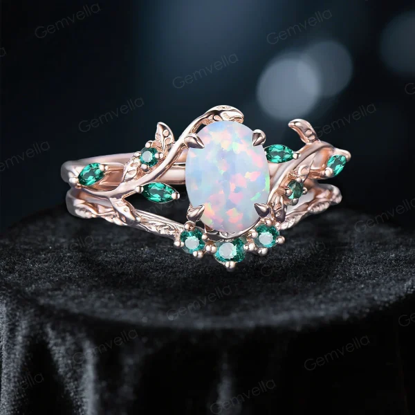 Angled view of 1.5ct oval white opal and emerald bridal ring set, displaying the 10K rose gold leaf vine branch design and natural gemstone details from a three-quarter perspective