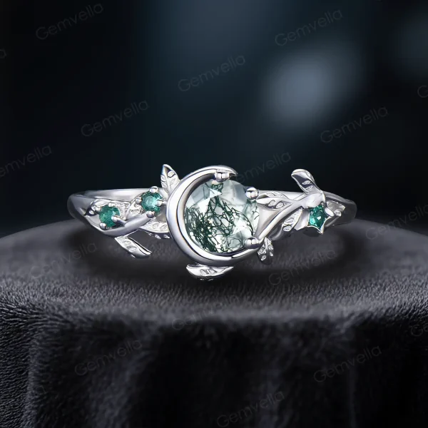 A delicate 925 sterling silver ring featuring a 1ct round moss agate stone. The design highlights a vintage moon and star theme with leaf green emerald accents, ideal for everyday wear or engagement.