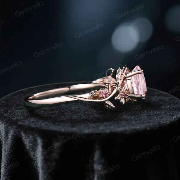 Side profile view showing the intricate leaf vine branch design and gallery work of this 14k gold pink sapphire engagement ring with pink tourmaline accents
