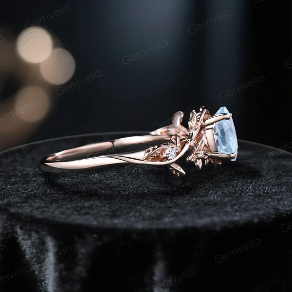 Side profile view showing the height and setting of the vintage Aquamarine engagement ring, highlighting the 14k gold band with detailed leaf vine branch motifs and the gallery structure holding the round moissanite accents.