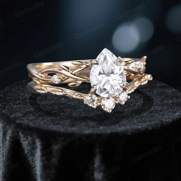 Side profile shot of the 1.25ct pear shaped moissanite ring on a rose gold plated band, highlighting the prong setting height, the curvature of the matching wedding band, and the organic vine texture.