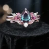 Oblique angle view of the 1.25ct pear alexandrite engagement ring set, displaying the three - dimensional design of the cluster - set main ring (with pink tourmaline and moissanite) and the complementary leaf - branch moissanite band.