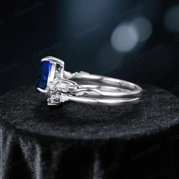 Side profile showing the delicate sterling silver twig and leaf motif wrapping around the band of the 1.25ct pear cut blue sapphire ring.
