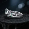 Side profile showcasing the substantial width of the sterling silver band, the raised cathedral setting of the Moss Agate, and the detailed leaf texture wrapping around the side of the ring shank with embedded Emerald stones.