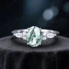 Front view of a handmade 1.5ct oval moss agate ring, featuring a central moss agate stone flanked by sparkling marquise and round moissanite accents, showcasing the vintage nature-inspired design.