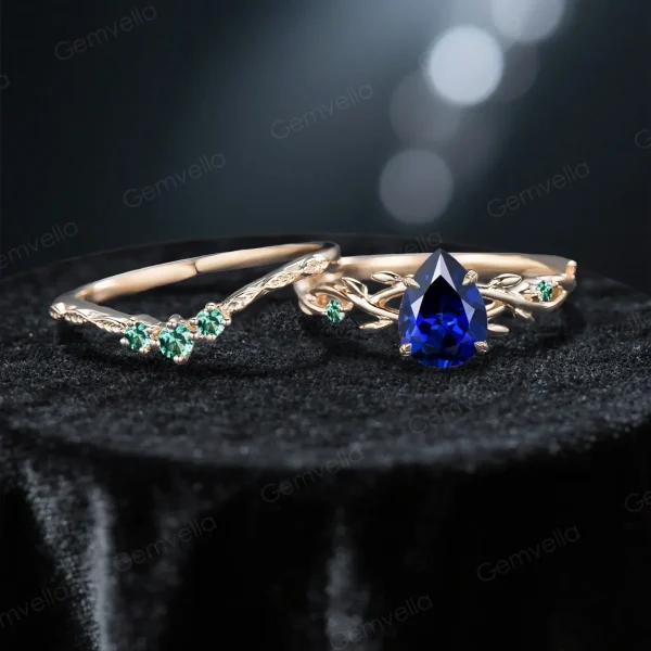 Flat lay photography of the nature inspired blue sapphire engagement ring and wedding band set separated to show the intricate emerald leaf details and the pear shaped blue gemstone.