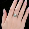 Lifestyle close-up of the vintage Moss Agate and Emerald ring set worn on a woman's finger, demonstrating how the twisting vine design wraps elegantly around the hand and complements the skin tone with its earthy green and vivid emerald hues.