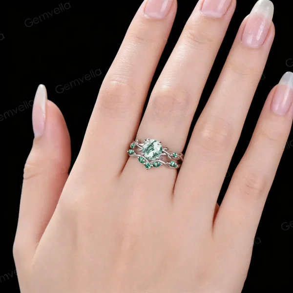 Lifestyle close-up of the vintage Moss Agate and Emerald ring set worn on a woman's finger, demonstrating how the twisting vine design wraps elegantly around the hand and complements the skin tone with its earthy green and vivid emerald hues.
