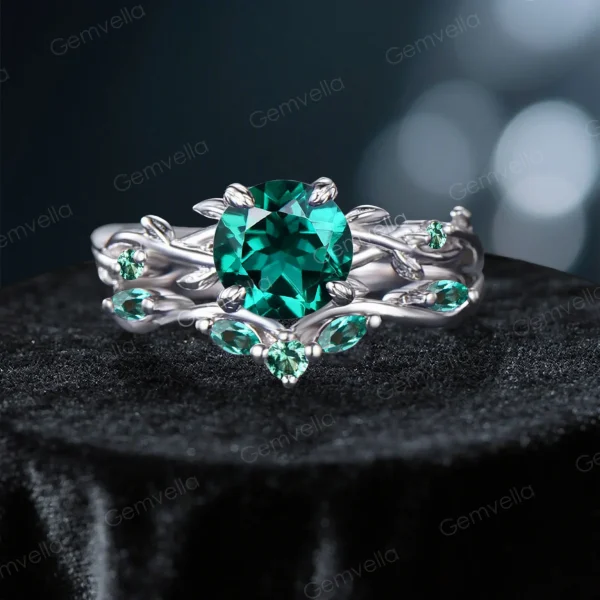 Front view of a vintage-inspired 1.2ct round cut green emerald ring featuring a twisting vine leaf design on the band.