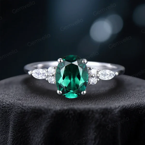 Stunning front view of an oval cut green emerald engagement ring featuring sparkling marquise moissanite accents set in silver.