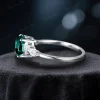 Side profile view showing the intricate setting and band design of the oval green emerald and marquise moissanite bridal ring.