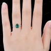 Lifestyle shot of a woman wearing the oval green emerald and moissanite engagement ring, highlighting the elegant look on the finger.